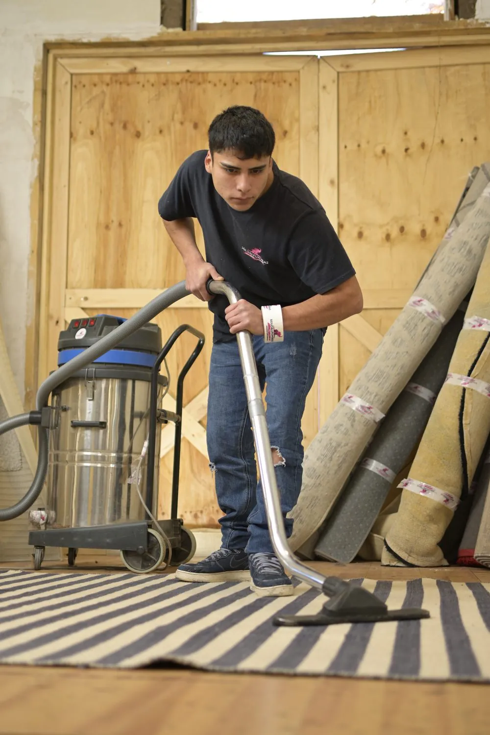 Aspirando entre alfombras enrolladas en la planta
